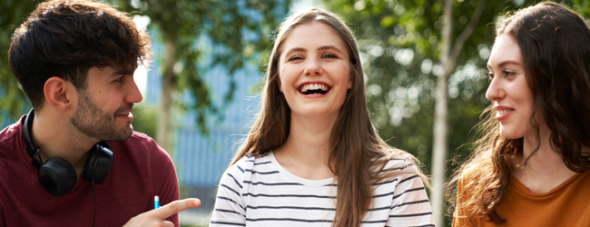 Drei junge Erwachsene lachen und unterhalten sich im Freien während einer LISA! Sprachreise