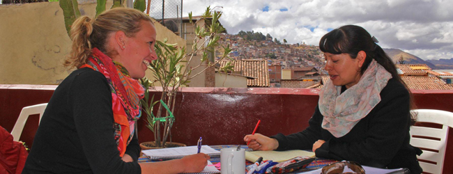 Lehrerin und Teilnehmerin im Einzelunterricht auf einer Terrasse mit Blick auf Cusco an der Sprachschule in Peru