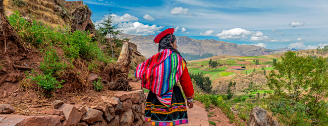 Sprachreisen: Frau in traditioneller bunter Kleidung wandert in einer malerischen Landschaft in den peruanischen Anden