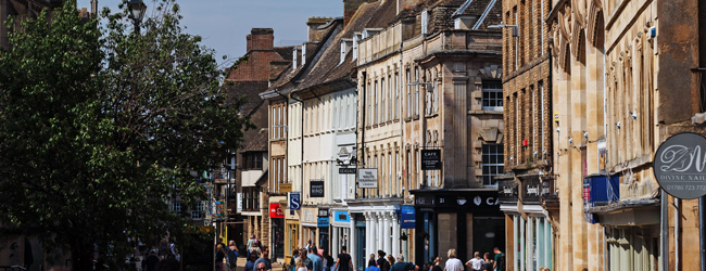 Menschen beim Einkaufen und Bummeln entlang einer historischen Häuserfront in Stamford