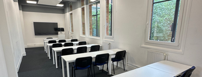 Unterrichtsraum in der LISA! Sprachschule für Schüler in Paris Bänke in Dreierreihen in einem Klassenzimmer mit großen fenstern bei einem Französisch-Sprachkurs für Schüler in Paris