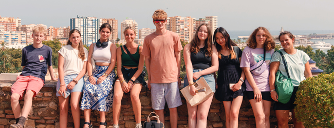 Jungen und Mädchen sitzen auf einer Mauer bei einer Schülersprachreise in Barcelona im Sommer